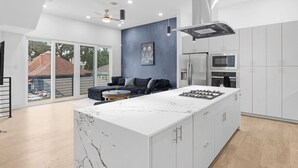 A modern kitchen with a large island, white cabinets, and a blue accent wall. - Newly Built Modern 3 Bedroom Houston Home (Houston)