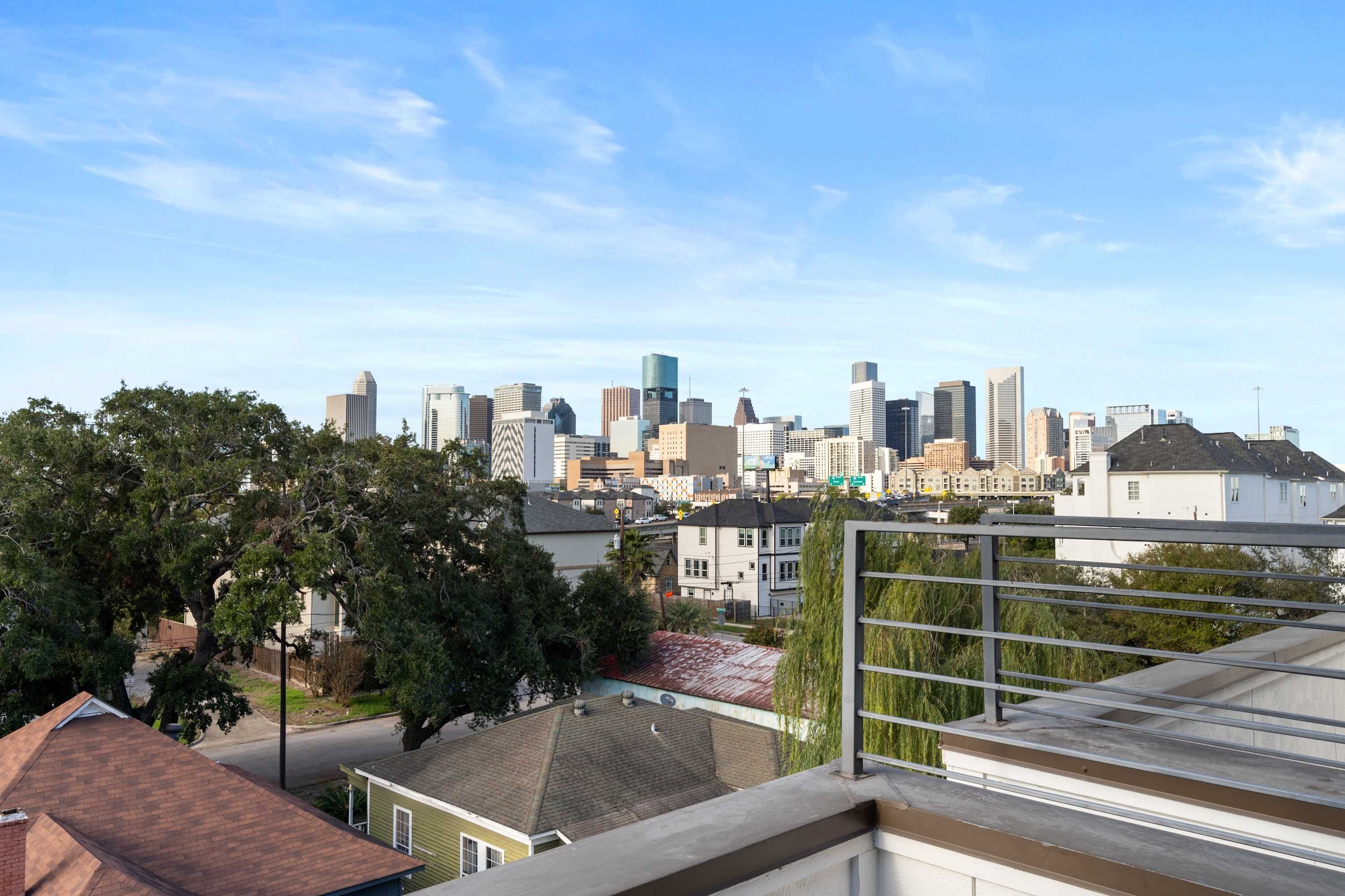 A city skyline with modern buildings, a residential area with houses, and a clear sky.