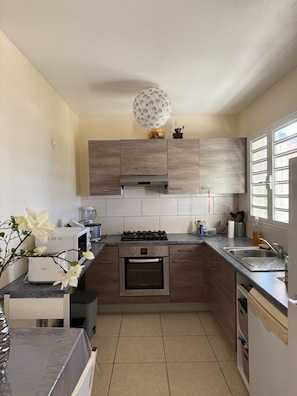 A modern kitchen with a gas stove, oven, and a large window providing natural light.