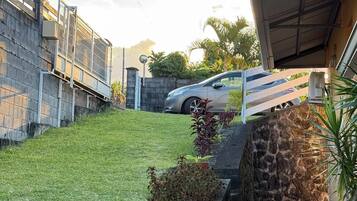 Una propiedad residencial con entrada en cuesta, un coche estacionado y un muro de piedra.