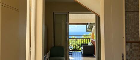 Ein Flur, der zu einem Balkon mit Meerblick führt, mit einem Sessel und einer Couch.