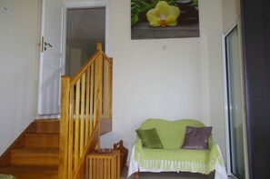A staircase leading to a room with a green sofa and a flower painting on the wall.