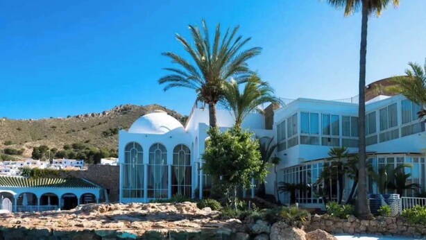 Ein Resort mit Pool, Palmen und einem Gebäude mit Rundbogenfenstern.