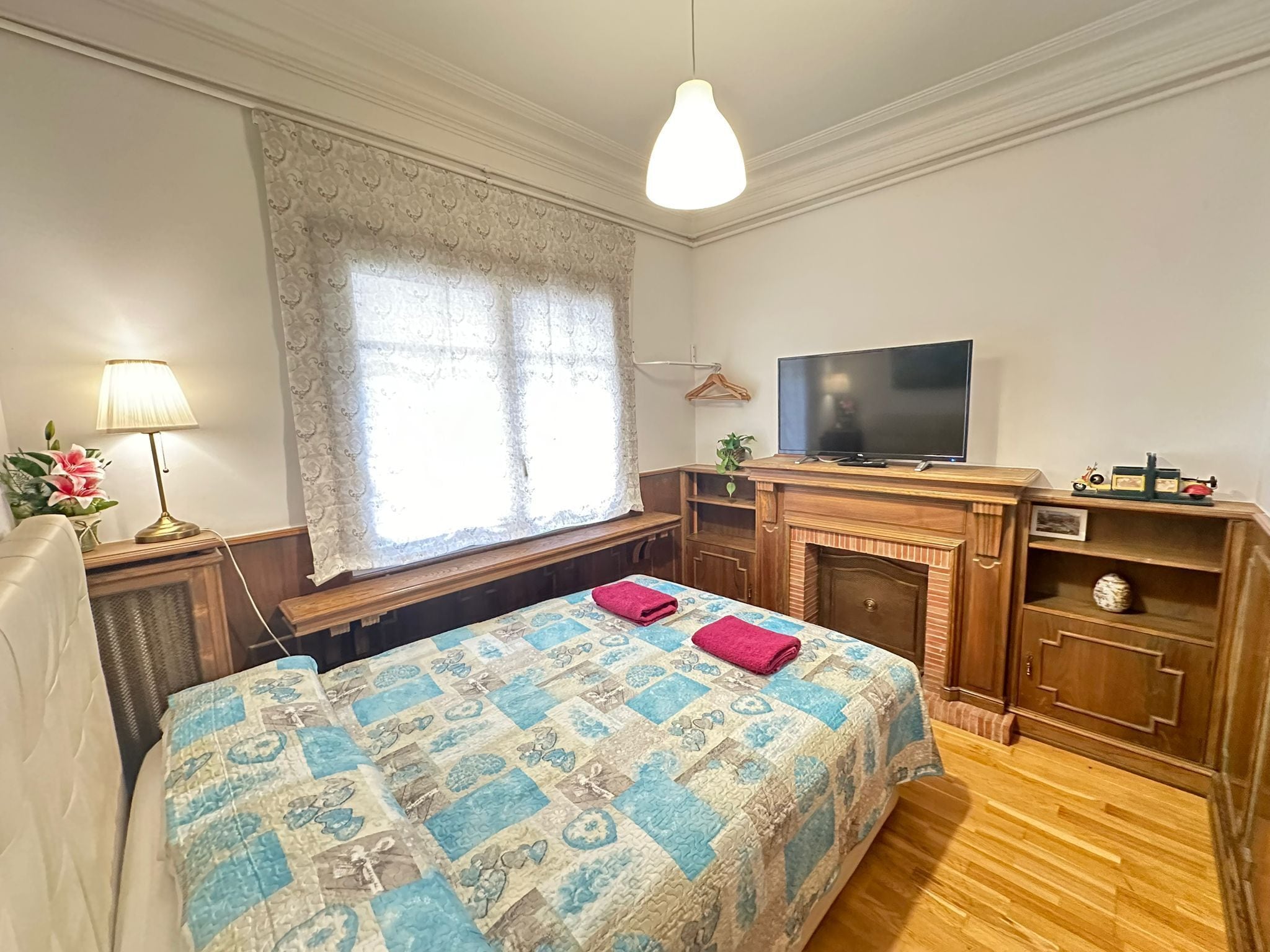 Un dormitorio con cama, televisión, chimenea y ventana con cortinas.