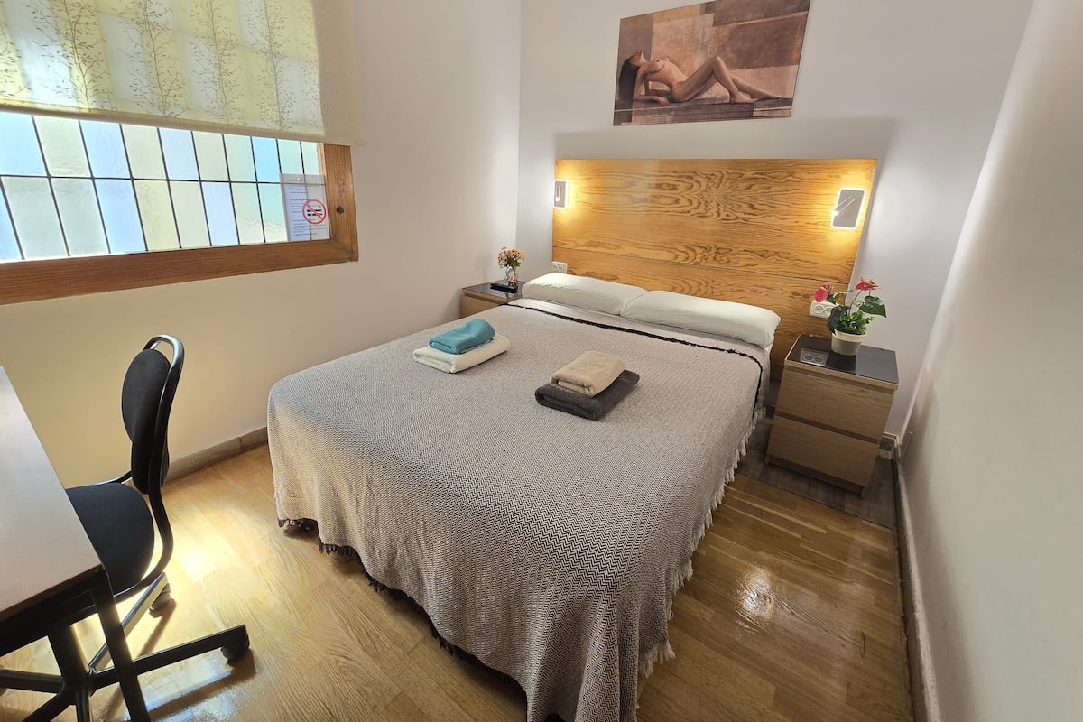 A neatly arranged bedroom with a bed, a desk, and a chair.