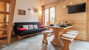 A cozy room with a black sofa, wooden dining table, and benches.