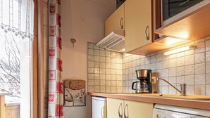 A compact kitchen with wooden cabinets, a microwave, a coffee maker, and a dishwasher.