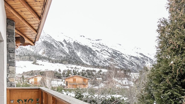 A wooden balcony with a view of snow-covered mountains.