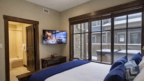 A bedroom with a large bed, a television on the wall, and a view of the outside through large windows. - Ski Ya Soon At Silver Star! 2 Bedroom Condo (Park City)