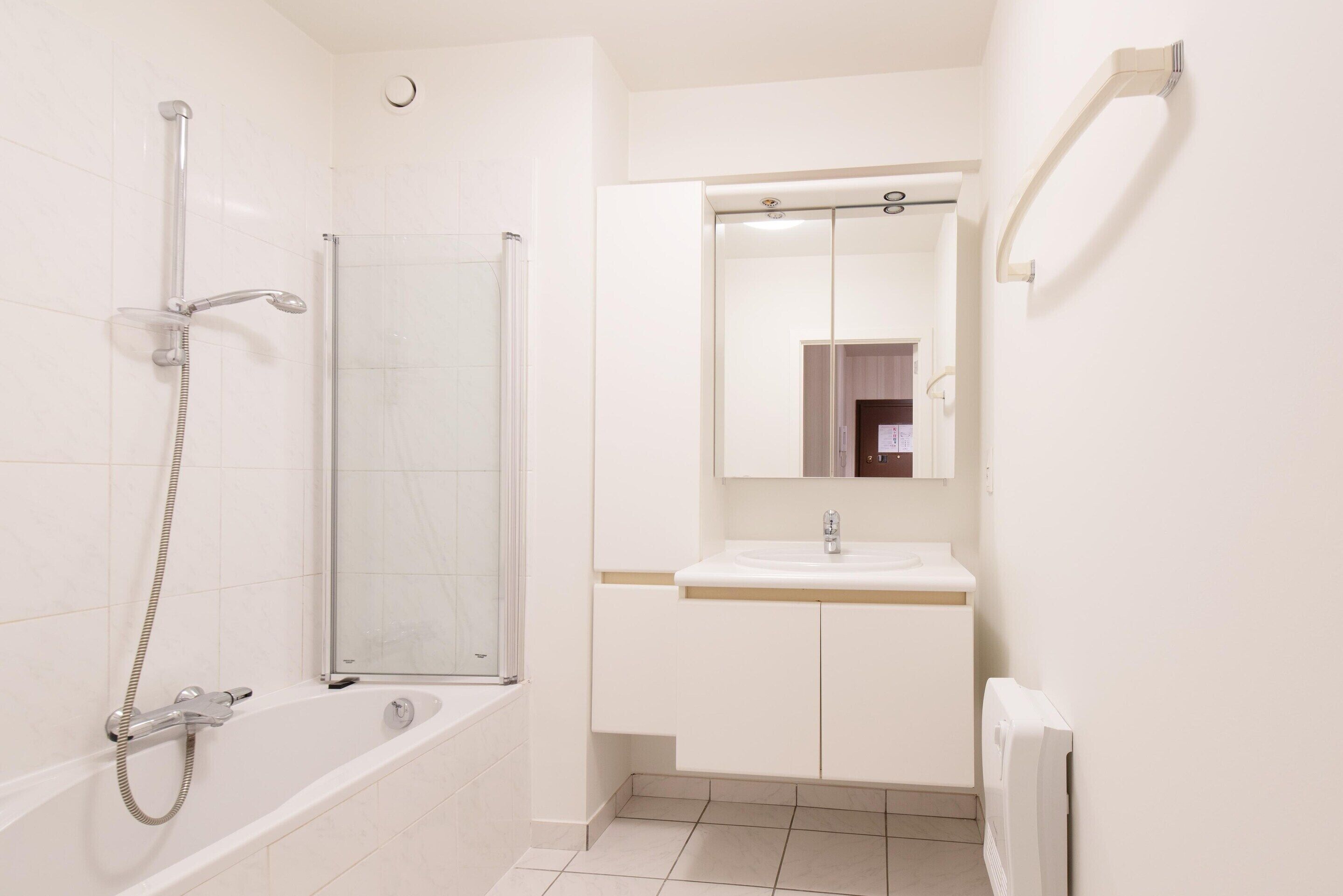 A bathroom with a bathtub, a glass-enclosed shower, a sink, and a mirror.