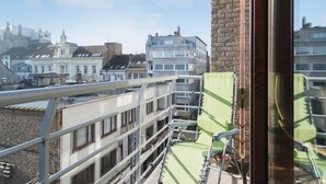 A balcony with metal railings overlooking a cityscape with various buildings. - Apartment in Belgium Near the Coast (Ostend)