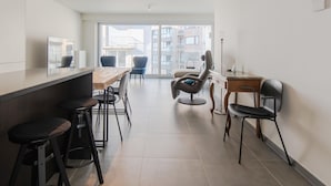 A modern kitchen with a bar area, bar stools, and a large window offering a view of the city. - Apartment Close to the sea Wall of Mariakerke (Ostend)