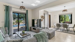 A modern living room with a TV, sofa, and dining area.