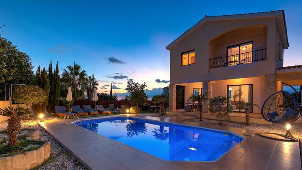A modern two-story house with a swimming pool, outdoor seating, and a hanging chair.