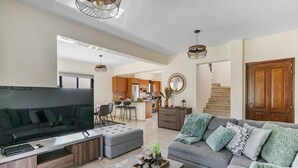 A modern living room with a large flat-screen TV, grey sofas, and a coffee table.
