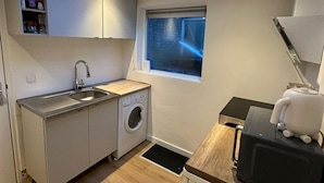 Una cucina compatta con un velux, una lavatrice, un lavello e un piccolo finestrino.