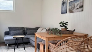 Un soggiorno accogliente con un divano grigio, un tavolo da pranzo in legno, sedie in vimini e una ventola a soffitto.