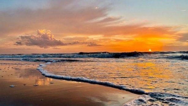 Una spiaggia al tramonto con le onde che lambiscono dolcemente la riva.