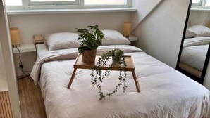Una camera da letto con un letto, un comodino con una pianta, uno specchio e una finestra.