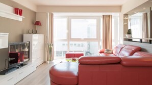 Un soggiorno moderno con un divano in pelle rossa, una televisione a schermo piatto e un'area pranzo con tavolo e sedie.