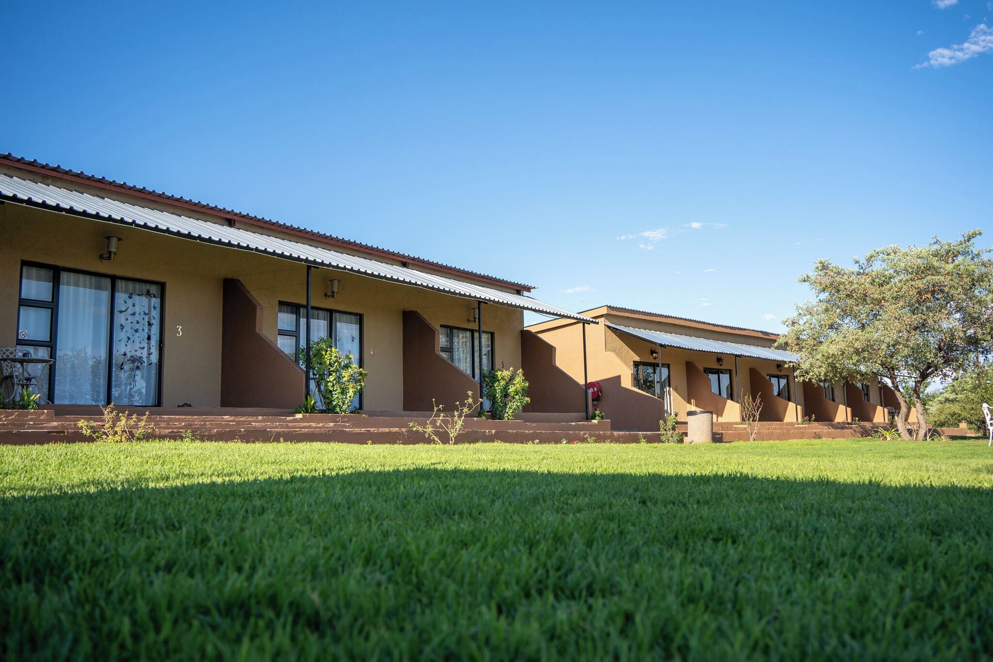 A row of two-story buildings with a flat roof, large windows, and a well-maintained lawn in front.