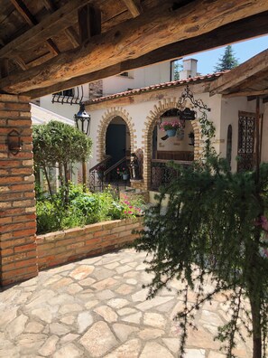 Un patio con suelo de piedra, paredes de ladrillo y arcos de entrada.