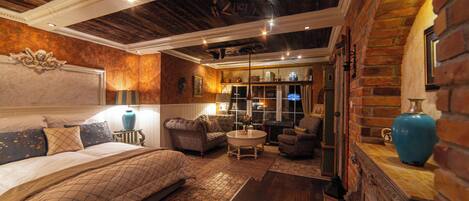 A cozy room with a bed, a seating area with sofas, a coffee table, and a fireplace.