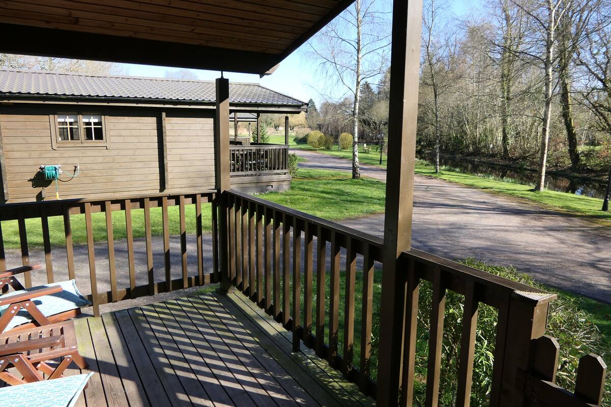 A wooden deck with a view of a road and trees.