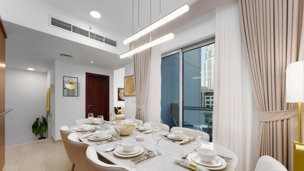 A dining area with a large oval table set for six, white chairs, and a view of the city through large windows.