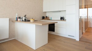 A modern kitchen with white cabinetry, a wooden countertop, and a built-in dishwasher. - Apartment in Ostend With Terrace (Ostend)