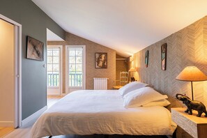 A bedroom with a large bed, a chair, a lamp, and a radiator. There are two windows and a door. - Magnifique maison basque avec piscine - Biarritz (Biarritz)