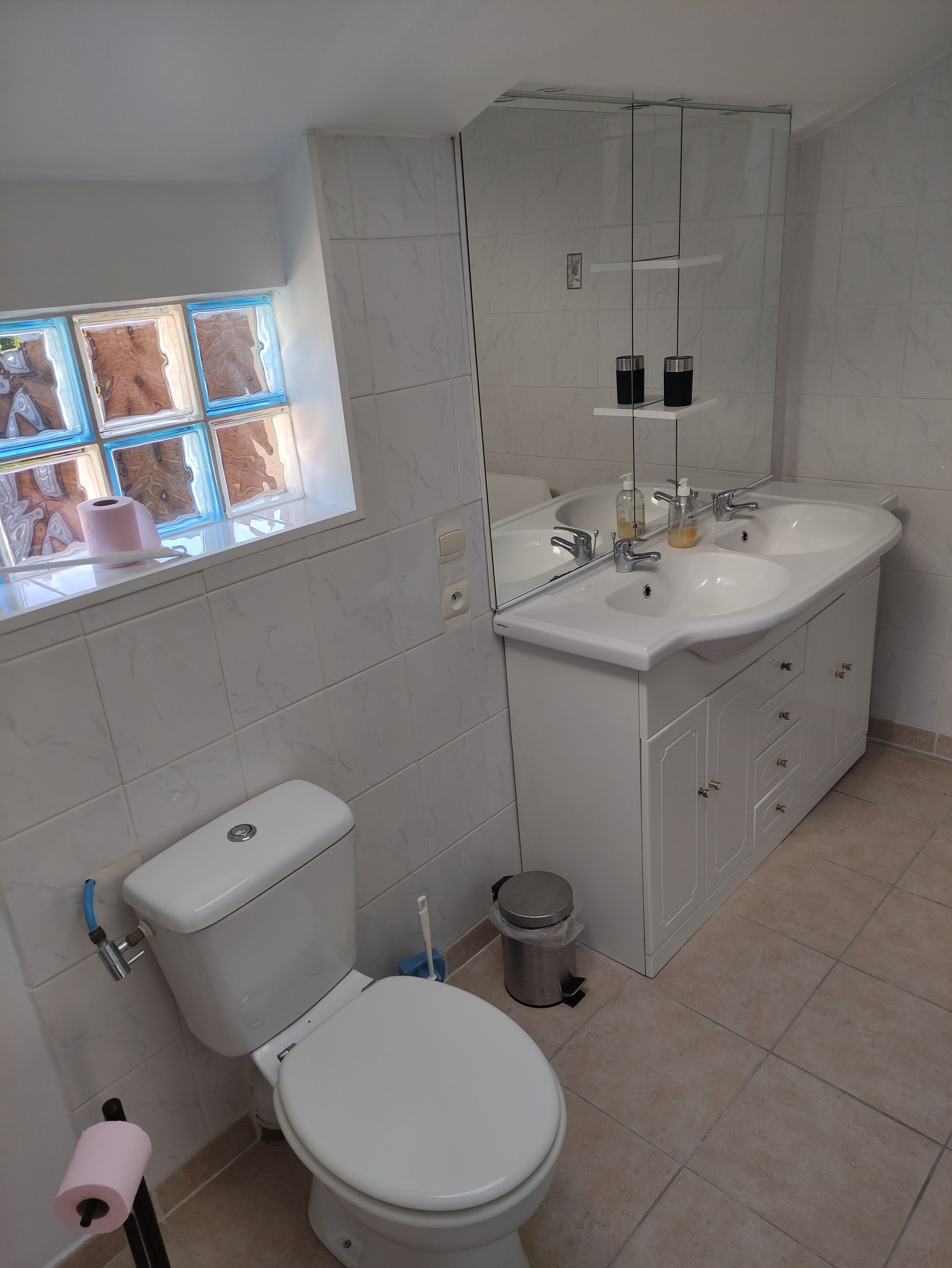 Une salle de bain avec des toilettes, un lavabo et une fenêtre.