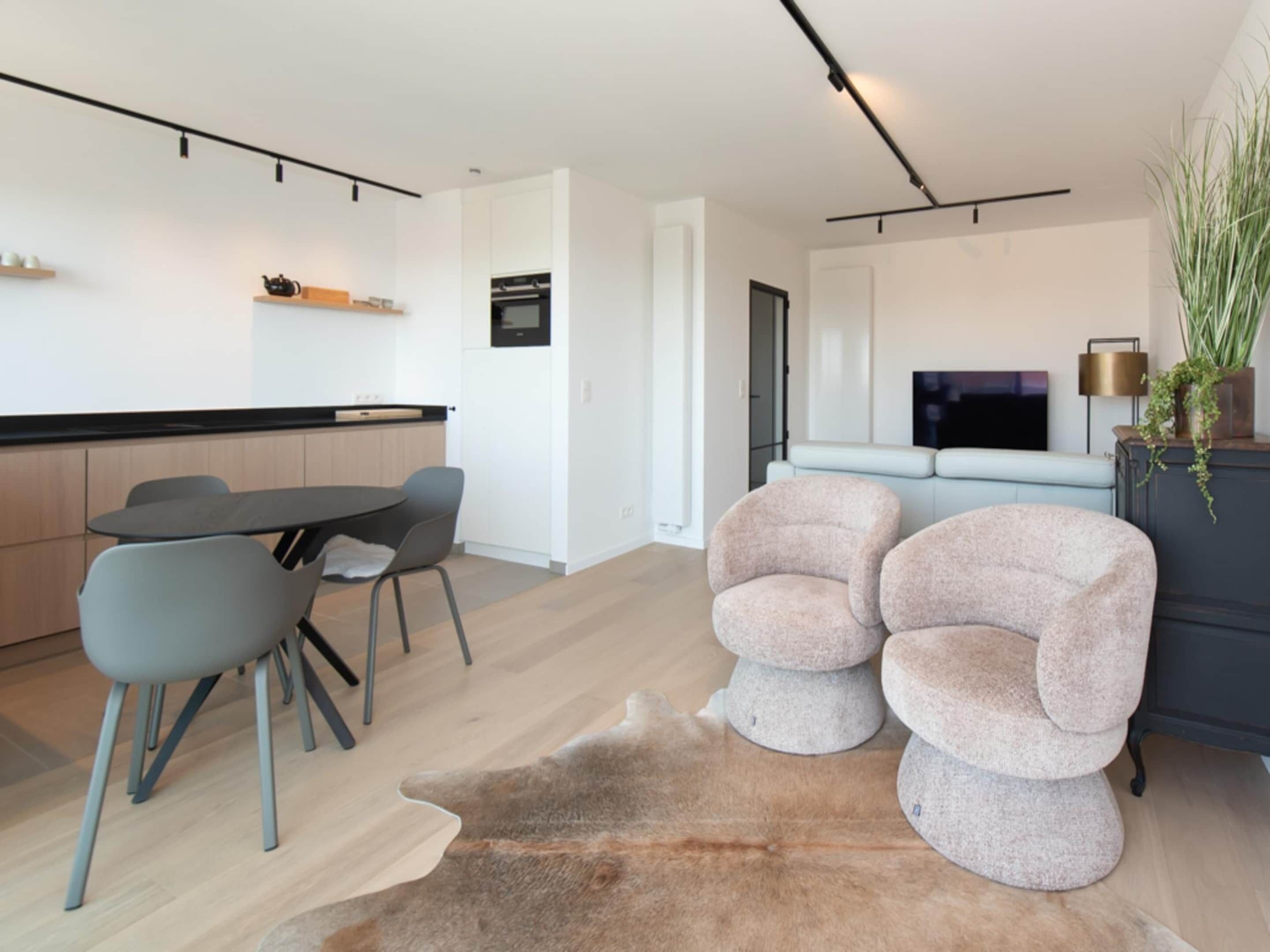 Ein modernes Wohnzimmer mit Essbereich, einer Couch und einem Fernseher.