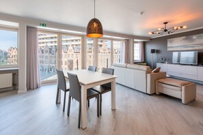 A modern hotel room with a dining area, sofa, and TV. - Apartment in Ostend With Marina Views (Ostend)