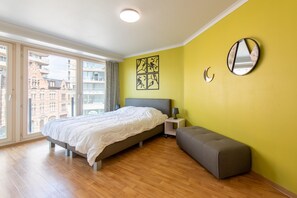 A bedroom with a bed, bedside table, bench, and artwork on the wall. - Apartment in Ostend With Marina Views (Ostend)