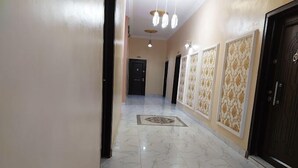 A hallway with marble flooring, a patterned rug, and a door with a decorative panel. - De Vegas Hotel (Nnewi)