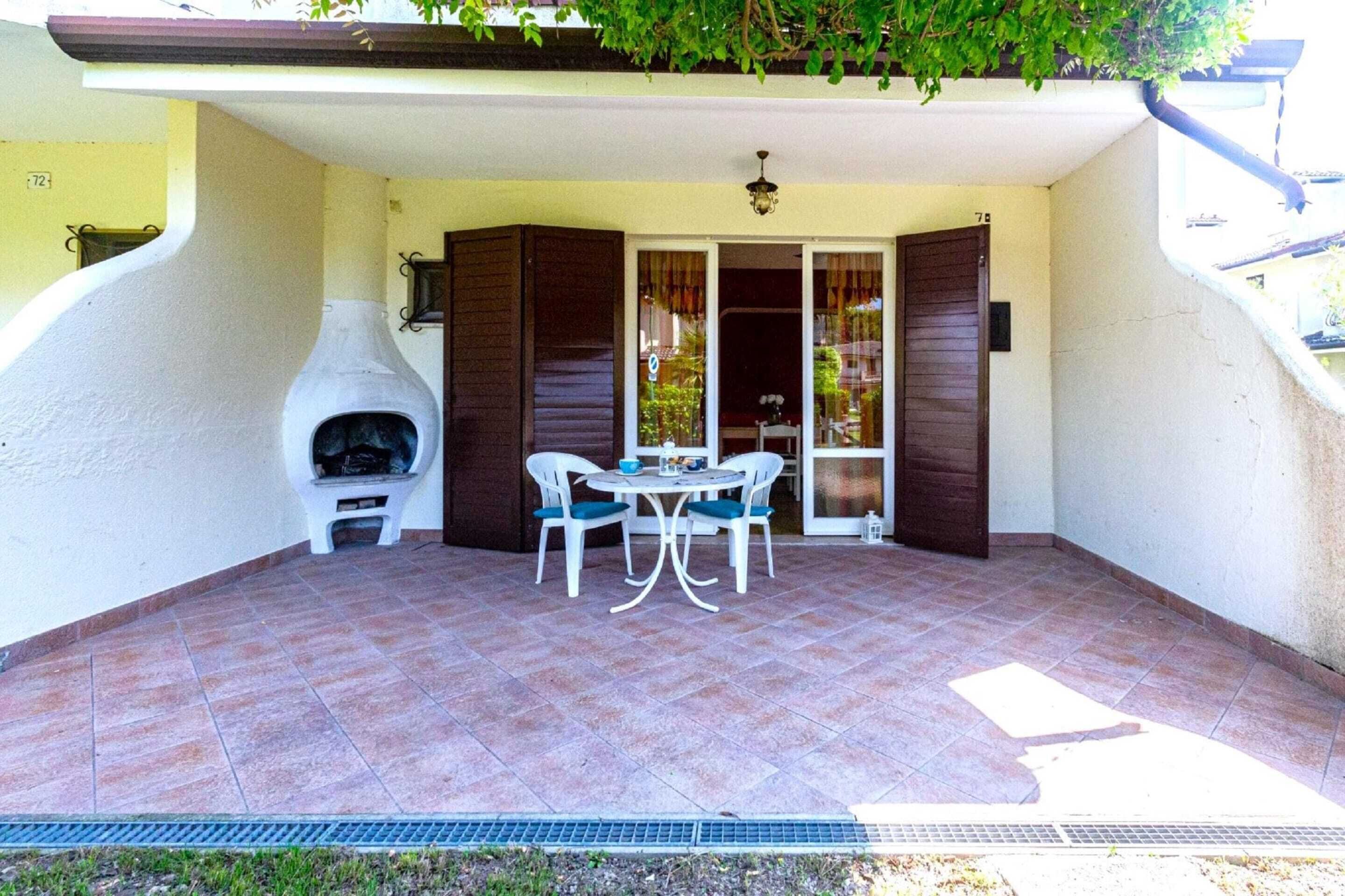 Une terrasse avec un barbecue, une table avec des chaises et une porte avec des rideaux.