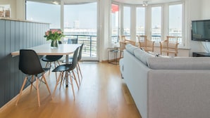 A modern living space with a dining area, sofa, and a TV. - Apartment in Ostend Near Shopping Street (Bons Villers)