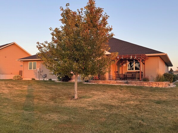 A residential house with a covered patio and a lawn.