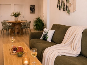 A living room with a sofa, a wooden coffee table with a glass of wine, a bowl of olives, and a plant. - Rêve d’Évasion — Escape Between Montpellier & the Sea (Lattes)