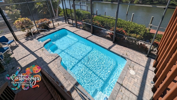 Ein rechteckiger Pool mit klarem, blauem Wasser, umgeben von einer Ziegelterrasse und einem Metallzaun.