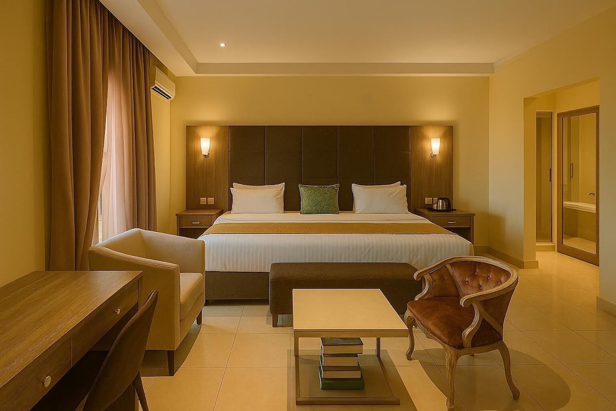 A hotel room with a large bed, two bedside tables, a desk, a chair, and a bookshelf.
