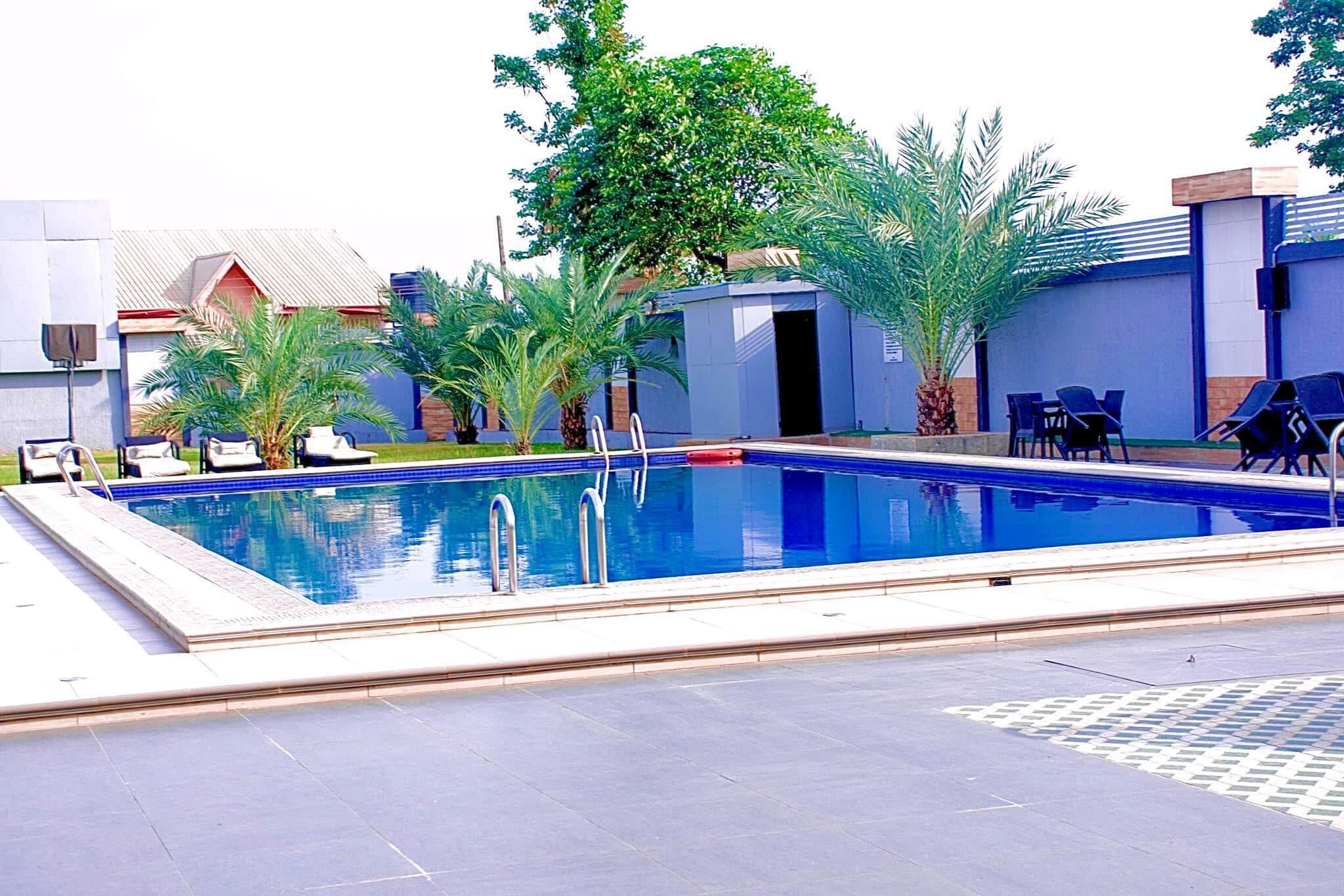 Una piscina con sillas de descanso y palmeras.