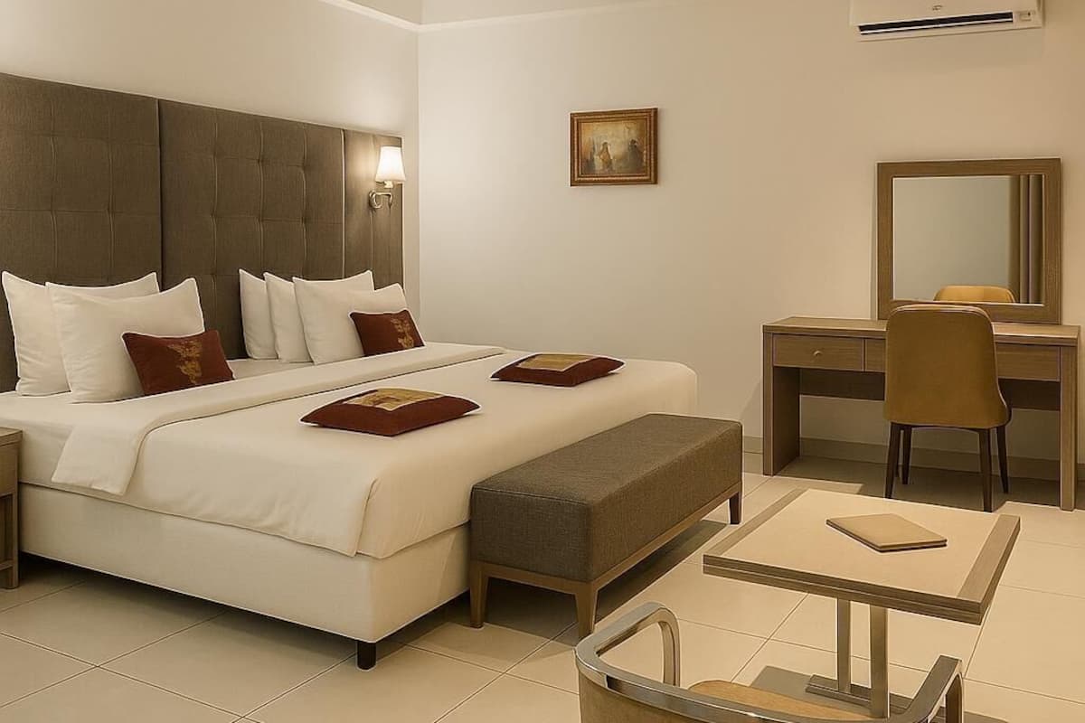 A modern hotel room with a large bed, a desk, a chair, and a small table.