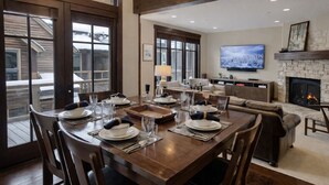 A dining area with a wooden table set for six, a sofa, and a fireplace.