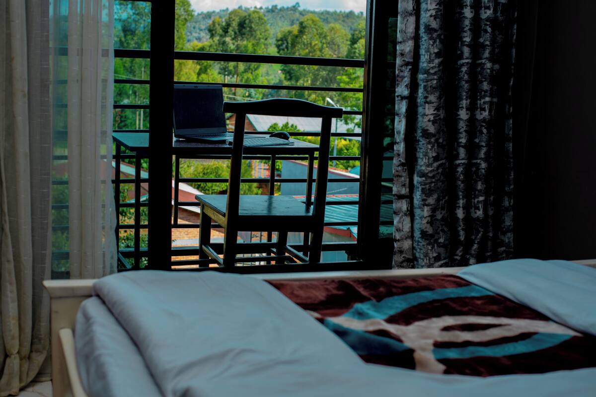 A bedroom with a bed, a desk with a laptop, and a chair.