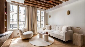 Un salon moderne avec un canapé, un fauteuil, une table basse et une vue sur la ville grâce à de grandes fenêtres.