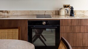 Une cuisine équipée d’armoires en bois, d’un four à micro-ondes, d’une machine à café et d’un lave-vaisselle.
