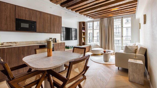 Une cuisine moderne avec des meubles en bois, un four à micro-ondes encastré et un coin repas comprenant une table ronde et des chaises.
