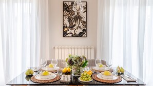 A dining table set for four with a centerpiece of flowers and fruit, a modern chandelier, and a large abstract painting on the wall. - The City Terrace Apartment: smart 2 bedrooms in Lucca (Lucca)